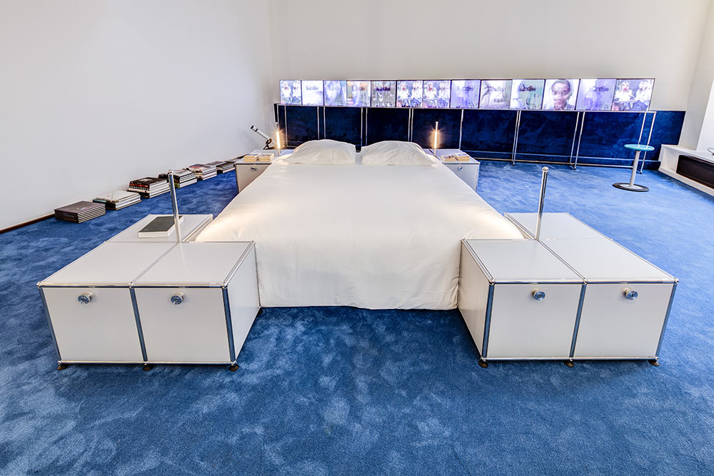 El segundo lugar de la instalación creada por USM y Copeni es un dormitorio. La cama está rodeada por mesitas formadas por módulos 