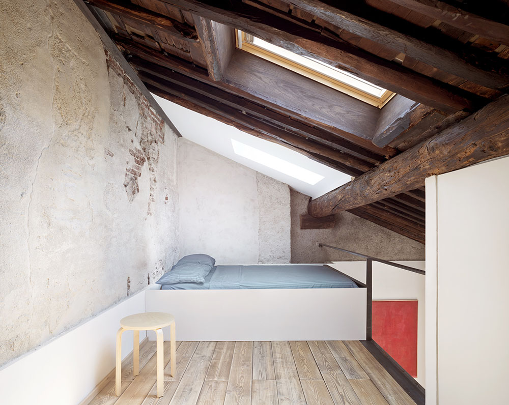 El dormitorio abuhardillado, solo cuenta con una cama de obra y  un taburte Frosta de Ikea