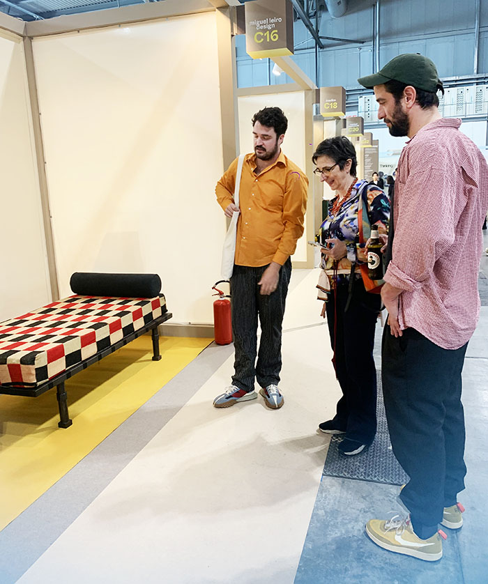 Miguel Leiro en su stand del SaloneSatellite 2023 mostrando su trabajo a la arquitecta Belén Moneo y al diseñador Lucas Muñoz.